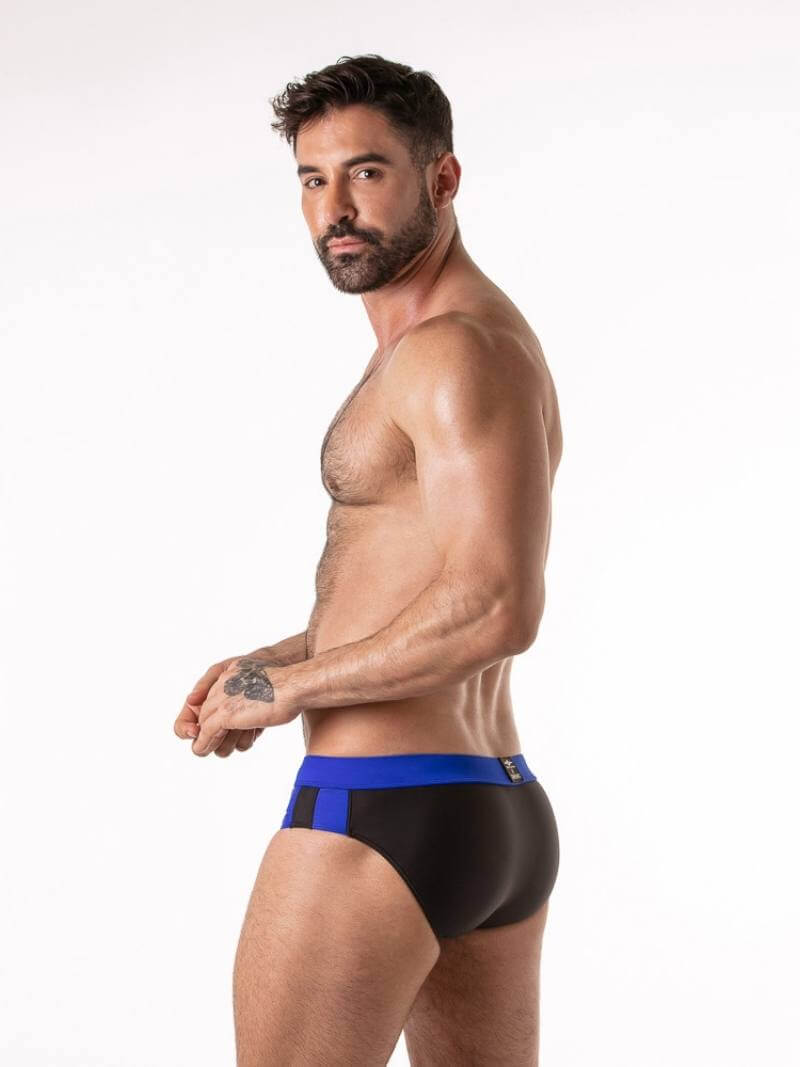 Man wearing black swim briefs with blue waistband on a white background