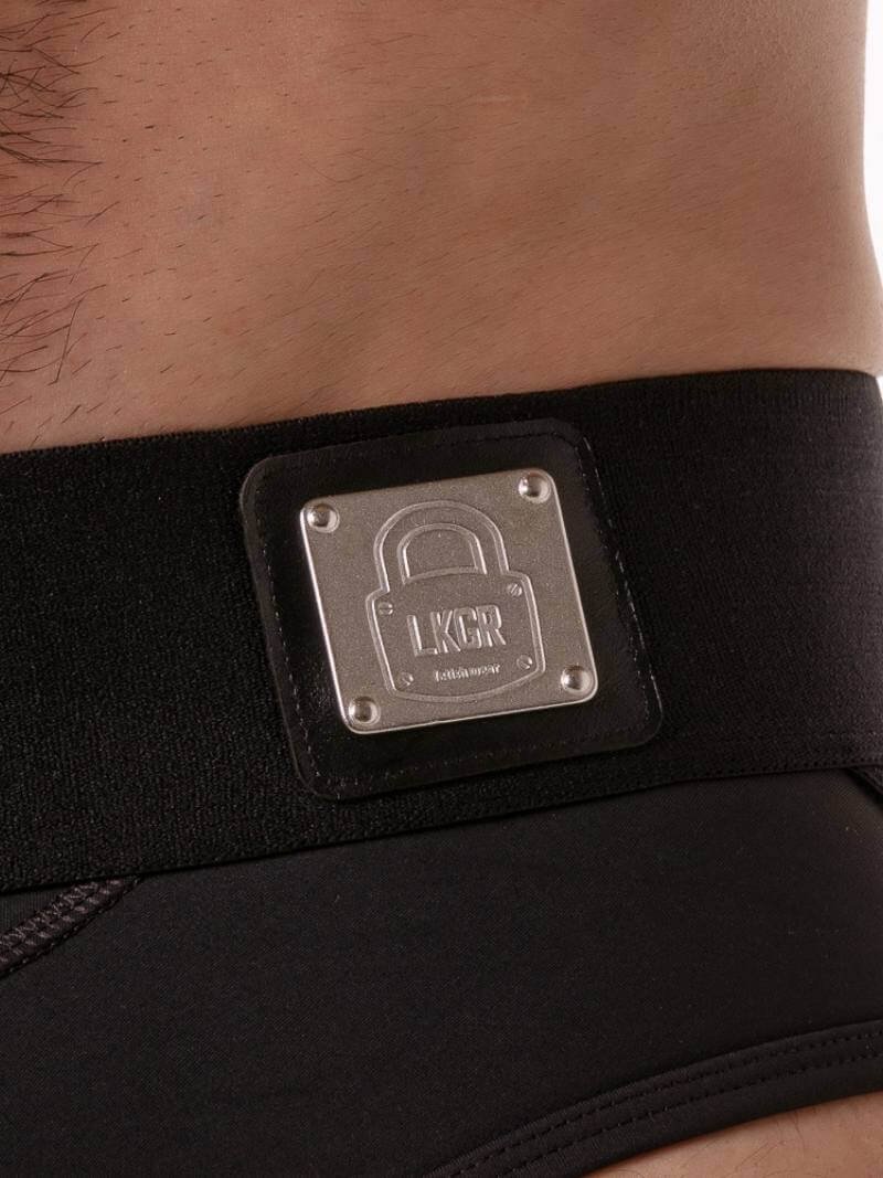 Black waist trainer with a metallic logo patch on a person's waist.