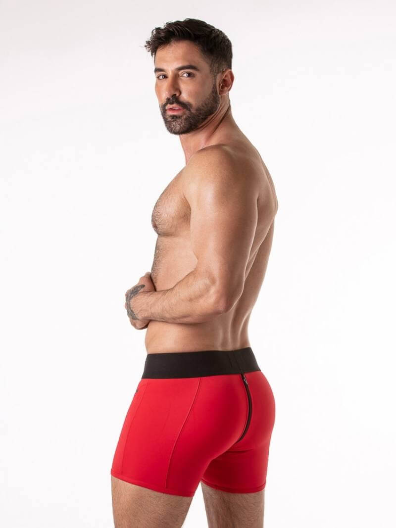 Man wearing red boxer briefs with a black waistband on a white background