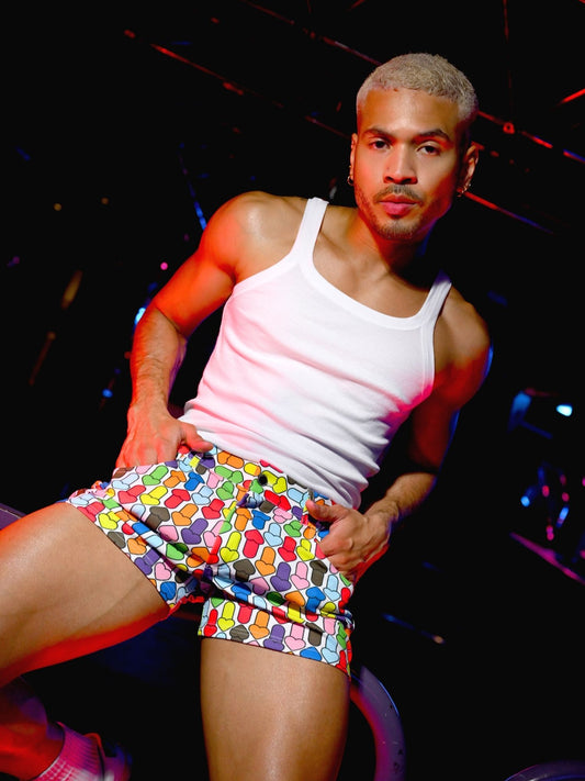 Man wearing a white tank top and colorful shorts against a dark background