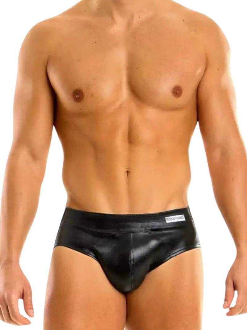This image features a sleek, bottomless leather brief by Modus Vivendi, modeled by a fit, hairless man. The brief is designed with a colored body, accented by a matching stitching and waistband, which highlights the brand’s logo.