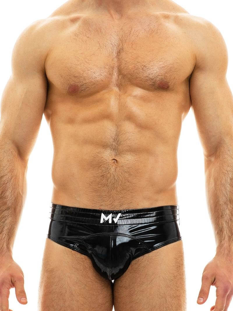 A man wearing a blue, shiny, bottomless PVC vinyl brief with an elasticated waistband and MV branding on the front.