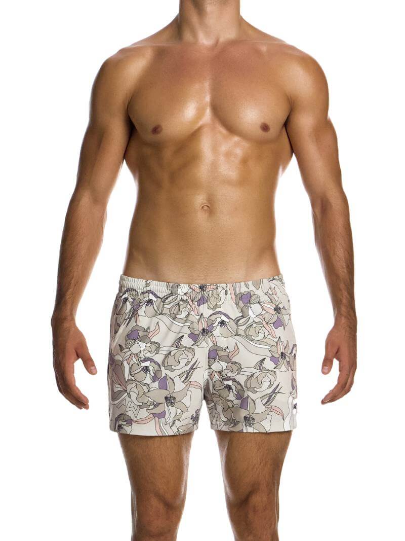 A man wearing art nouveau floral print swim shorts with elastic waistband and side pockets.