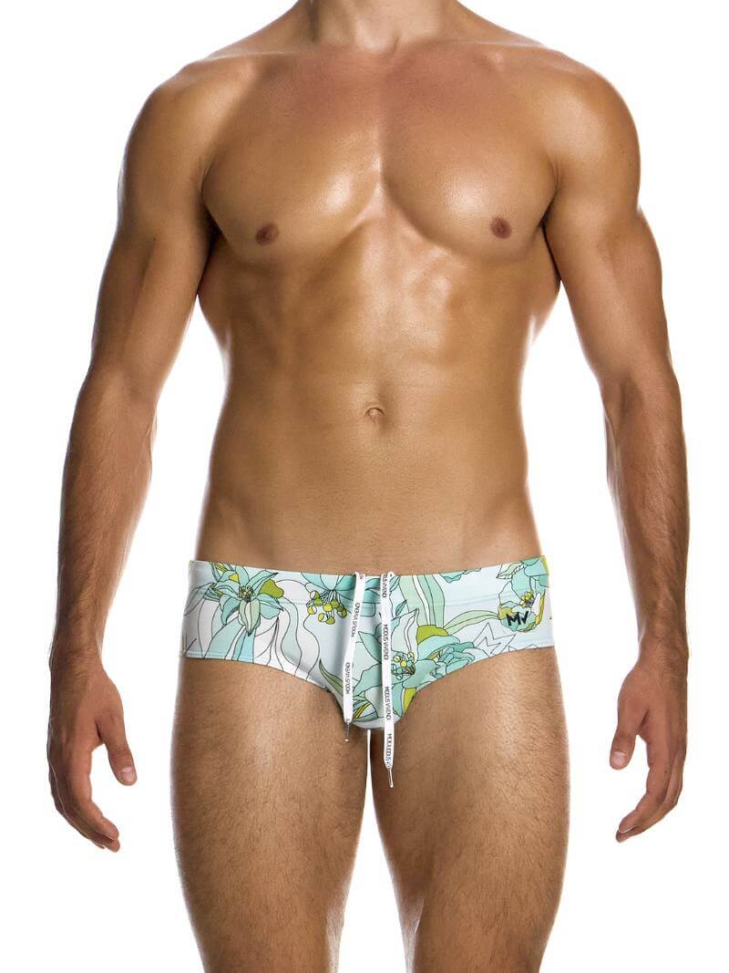 A male model wearing a Modus Vivendi Art Nouveau floral swim brief in pastel colors with a transparent brand label.