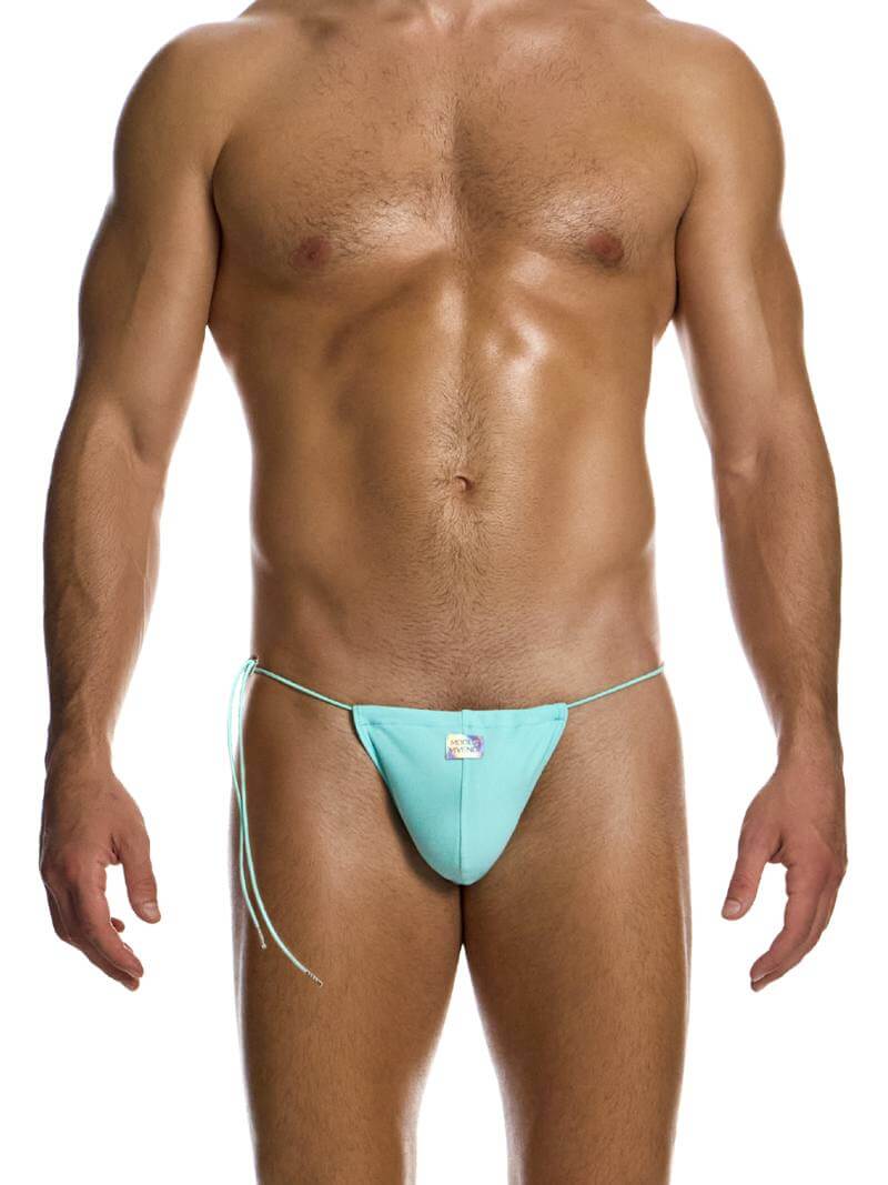 A male model wearing a yellow or mint green swimwear tanga with side tie strings and a shiny holographic Modus Vivendi logo.