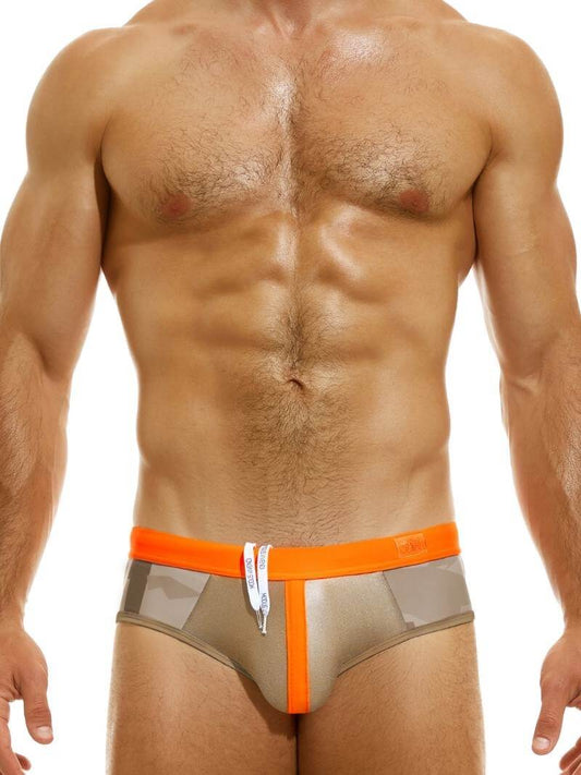 This image features the MODUS VIVENDI Desert Swim Brief, designed with a distinctive geometric desert camo print and a shiny metallic panel accented with fluorescent neon detailing. The swim brief stands out with its vibrant neon waistband and pouch stripe, providing a bold and eye-catching look.