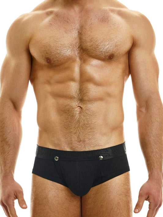 This image features a male model wearing the Modus Vivendi Hole Bottomless Brief, available in classic black, white, or grey colorways. The brief is designed with a backless style and a removable pouch, which is fastened with metal poppers and can be fully removed for a crotchless look.