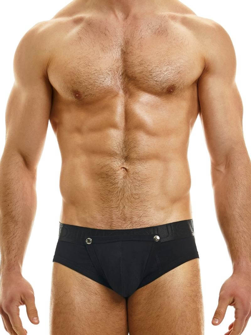 This image features a model wearing the Modus Vivendi Hole Brief, which showcases a classic black colorway with a matching shiny and branded waistband. The brief is designed with an daring and provocative feature of a removable pouch, which is fastened with metal poppers and can be removed for a crotchless appearance.