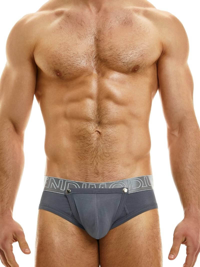 This image features a model wearing the Modus Vivendi Hole Brief, which showcases a classic black colorway with a matching shiny and branded waistband. The brief is designed with an daring and provocative feature of a removable pouch, which is fastened with metal poppers and can be removed for a crotchless appearance.