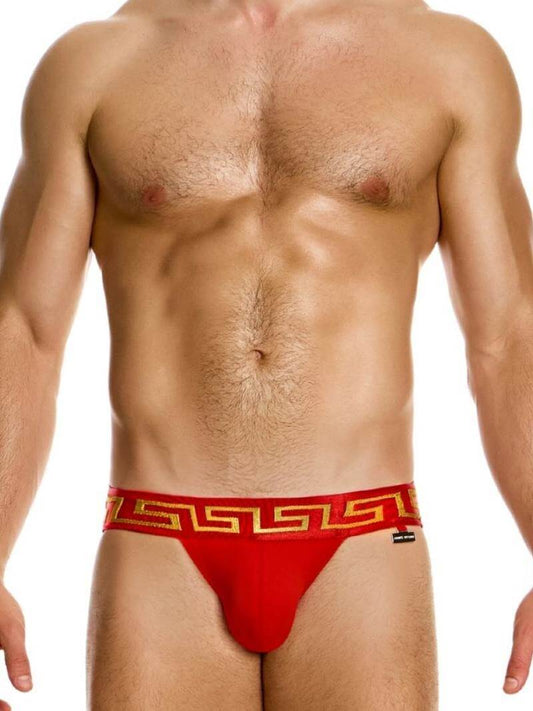 A model wearing a red jockstrap with a Meander Greek Key print waistband and a gold or silver Modus Vivendi charm logo.