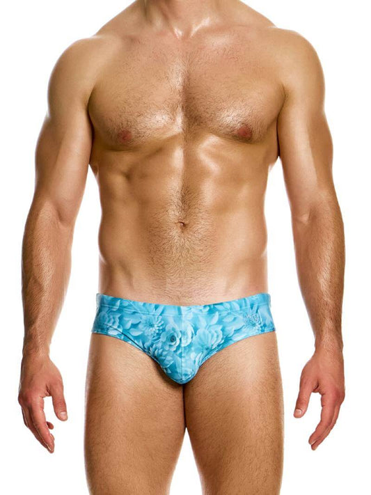 A model wearing blue floral origami swim briefs with a transparent brand label on the waistband.