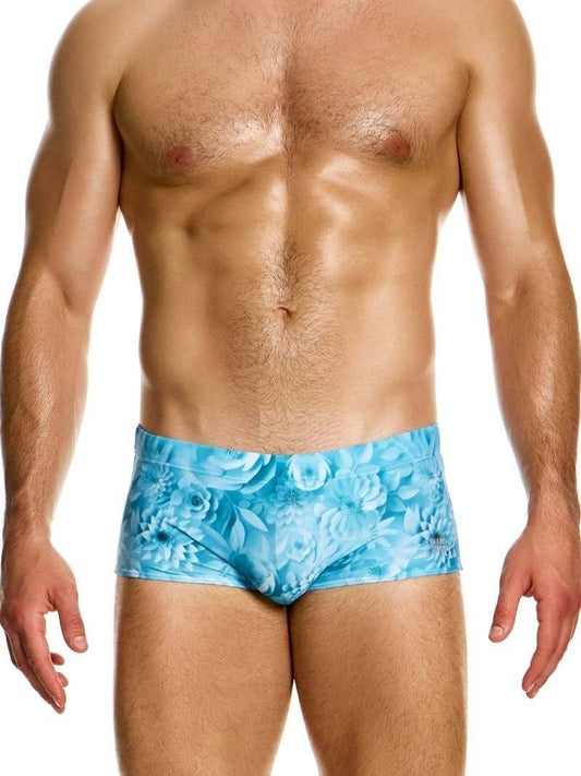 Man wearing blue floral swim briefs on a white background