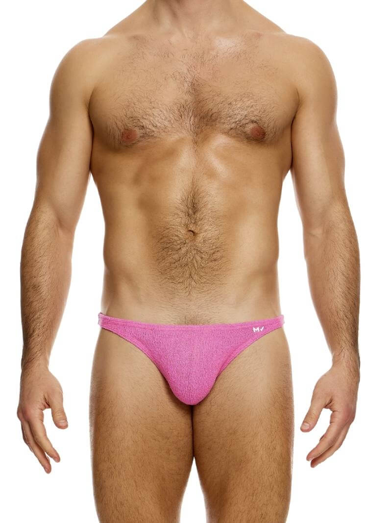 A model wearing a pink mini brief with a low-rise waist and high-cut legs, branded with a small MV logo on the waistband.