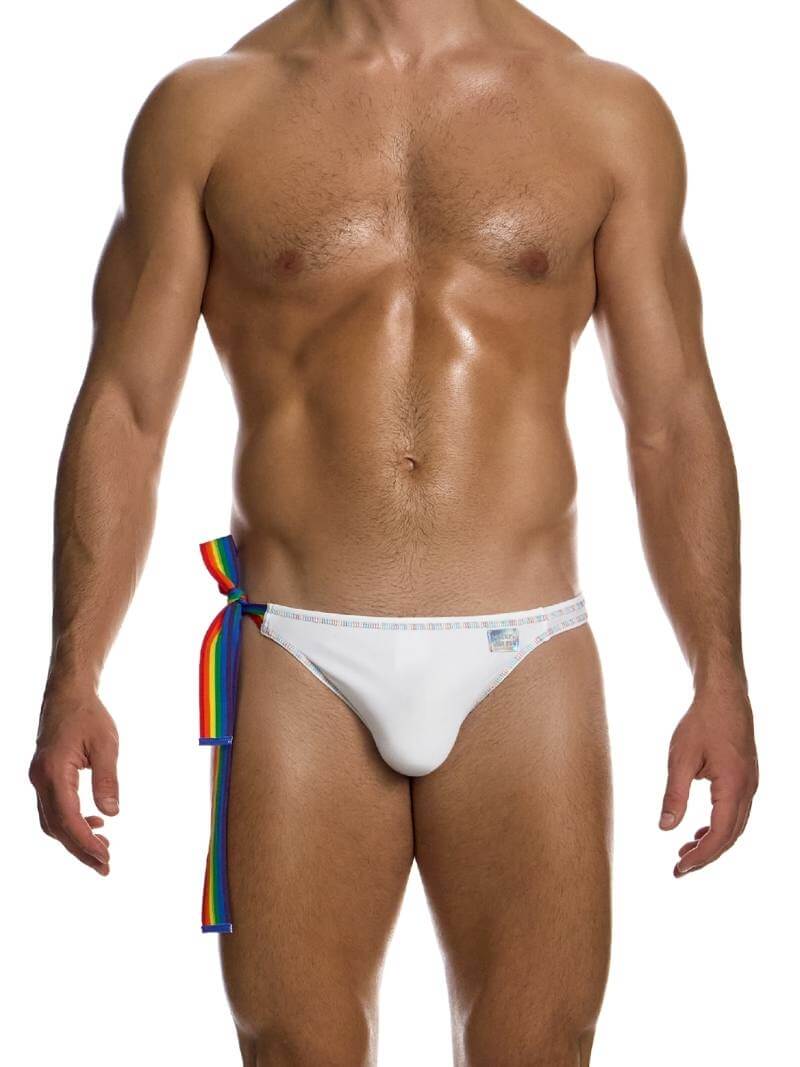 This image features the MODUS VIVENDI Pride Swimwear Thong, designed with a white body and highlighted with rainbow-colored stitching. The swimwear includes a rainbow-striped side ribbon and a shiny holographic sewn Modus Vivendi logo, adding a distinctive touch of style and pride.