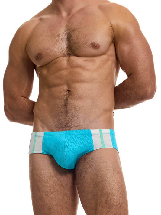 A model wearing a green retro micro brief with red and white stripes on the waistband.