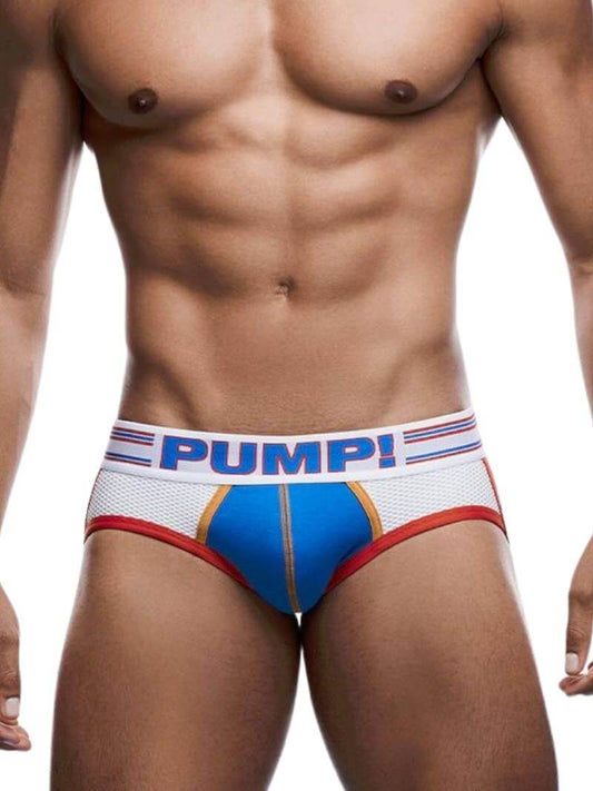 A model wearing a PUMP Underwear Velocity Jockstrap with white and blue multi-panel body, red elasticated jock straps, and a striped waistband with PUMP branding.