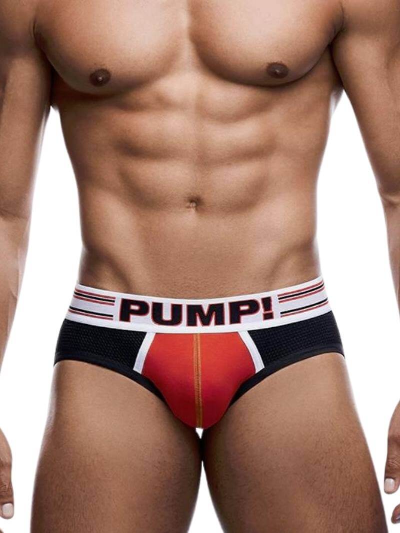 A model wearing a red and black PUMP Circuit jockstrap with contrasting white and black piping and a striped waistband.