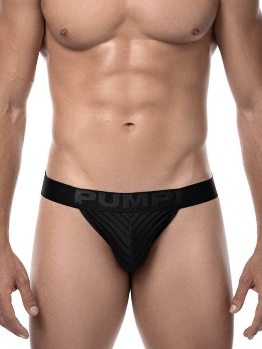 A model wearing a black PUMP! Whisper jockstrap, which has a matte waistband with satin logos and an alternating striped pattern of solid and transparent stripes.