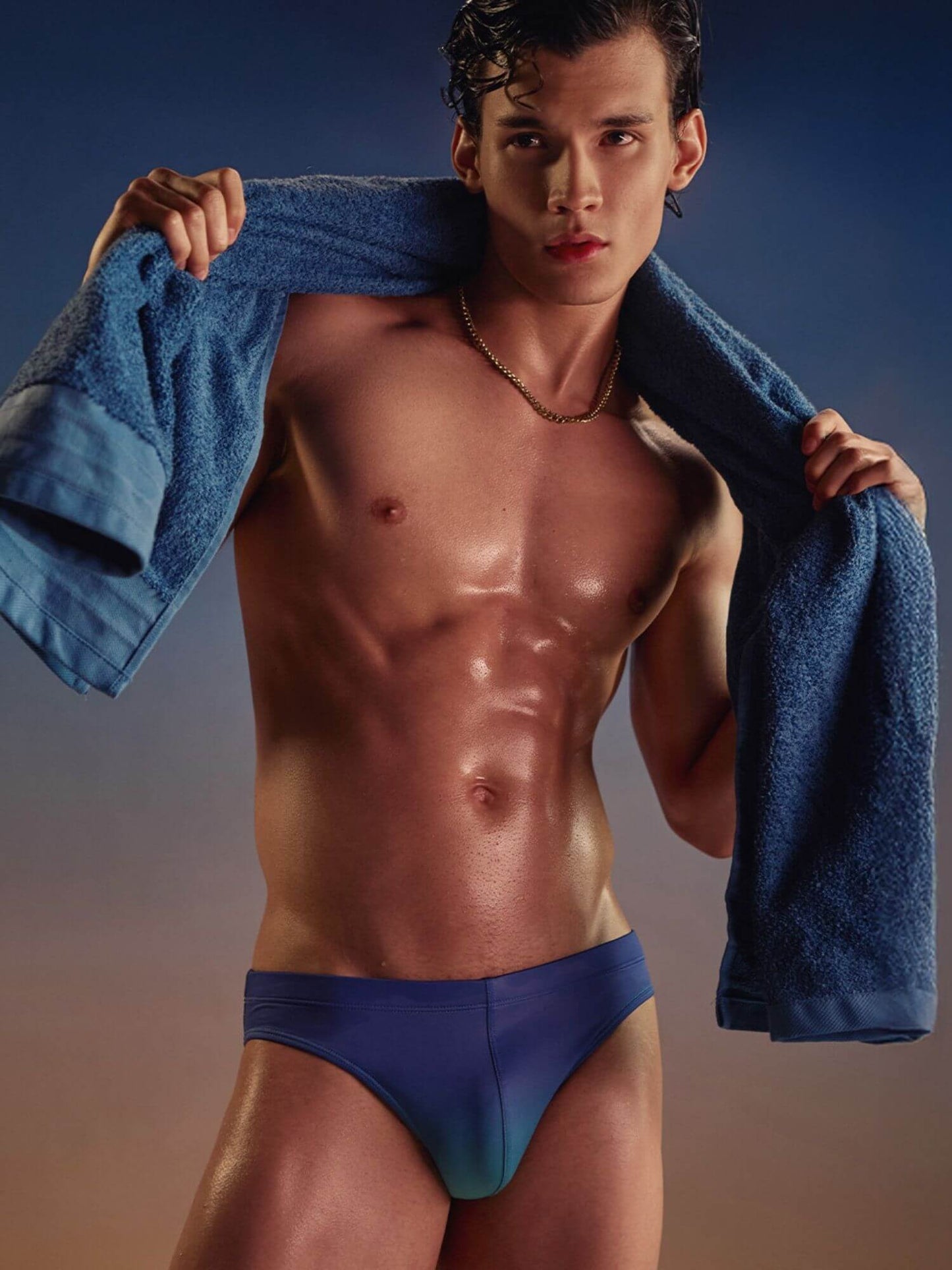 Man holding a blue towel over his shoulder against a gradient background