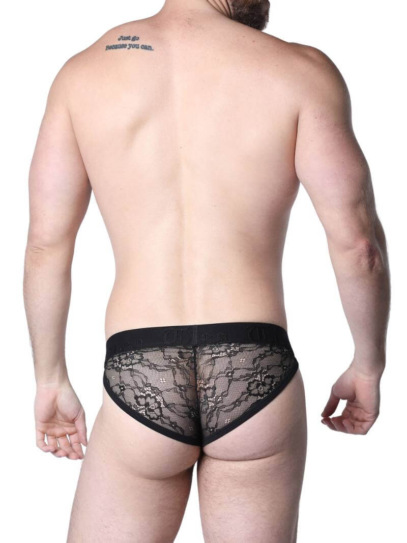 Man wearing black lace underwear standing in an urban setting.