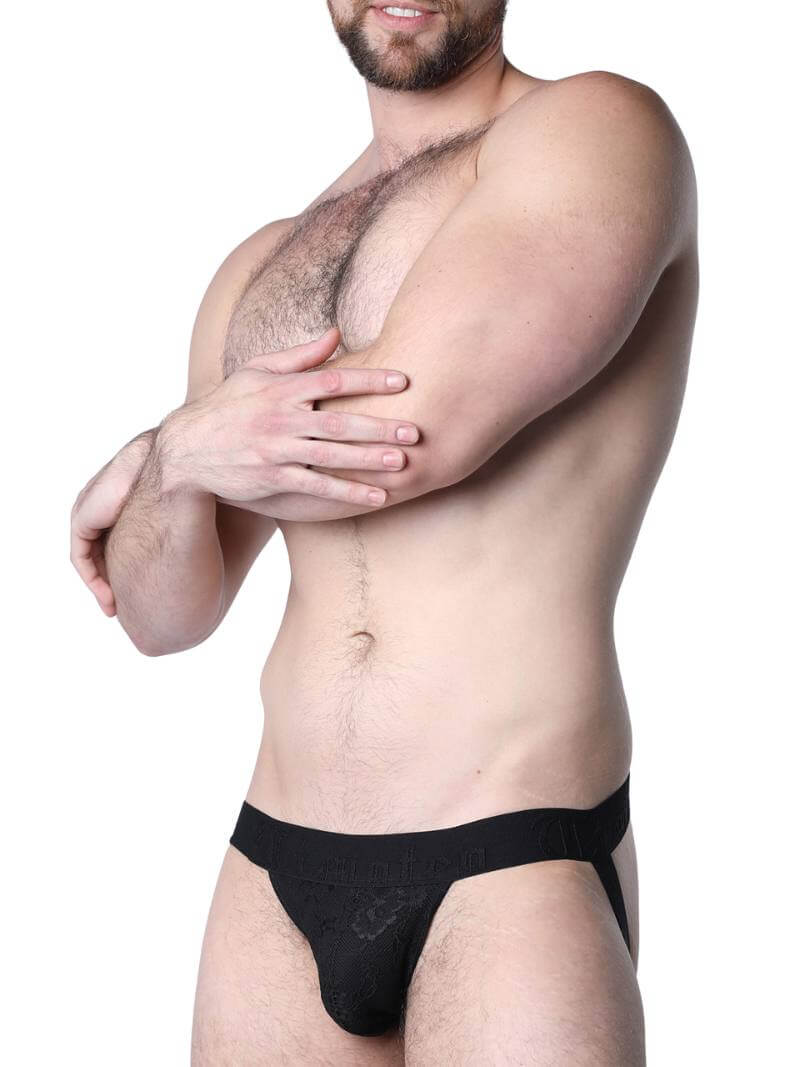 Man wearing a black lace lingerie set against a neutral background