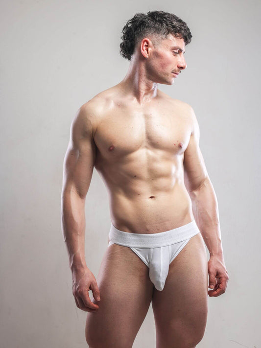 Man wearing a white jockstrap against a plain background