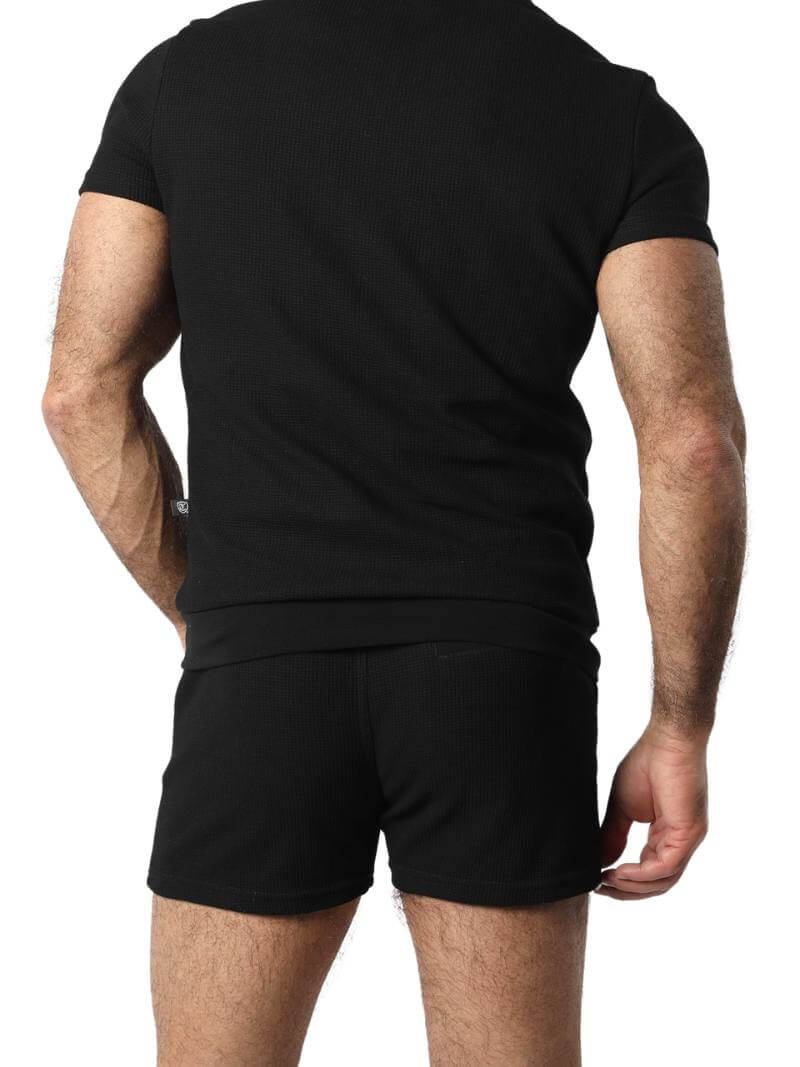 A man wearing mid-thigh length pink knitted shorts with a drawstring waist.