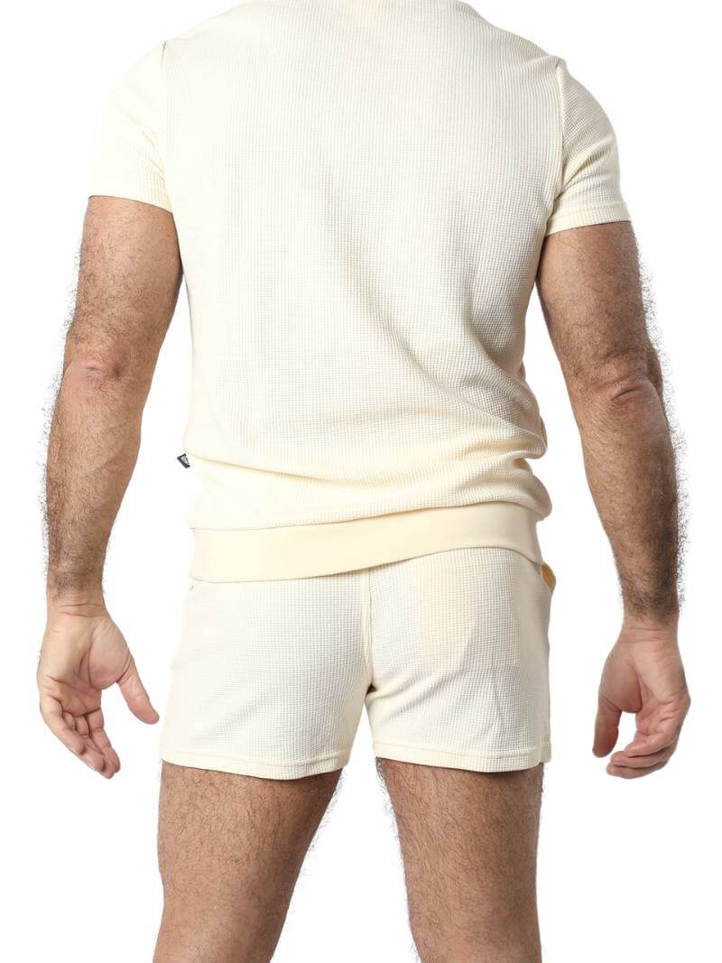 Close-up of a person wearing beige shorts and a matching top against a white background