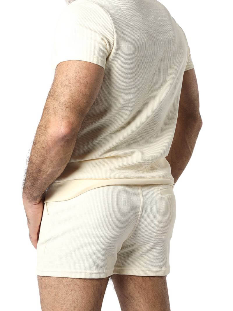 Close-up of a person wearing beige shorts and a matching top against a white background