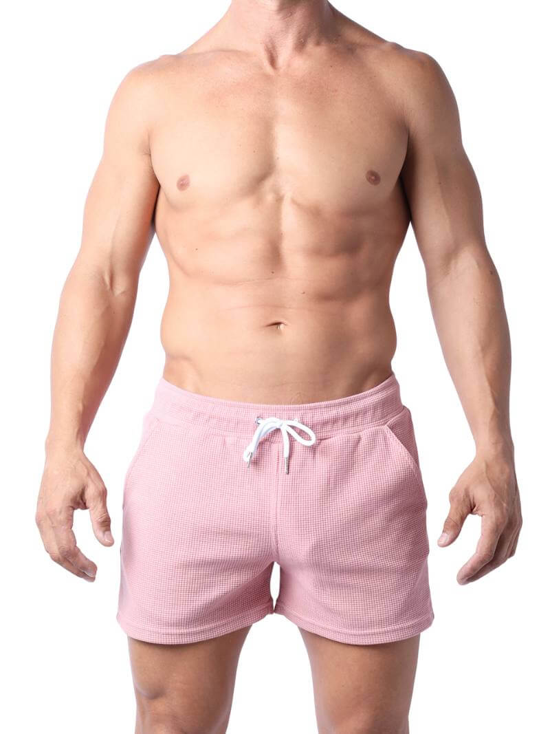 A man wearing mid-thigh length pink knitted shorts with a drawstring waist.