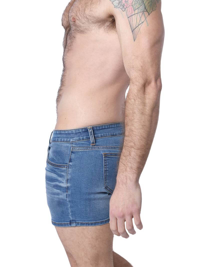 A pair of denim booty shorts with a low-rise waist and a 4-inch inseam, featuring a zipper fly, button fastening, belt loops, and four pockets. The shorts are blue with contrast stitching, and there is a leather branded patch on the back.