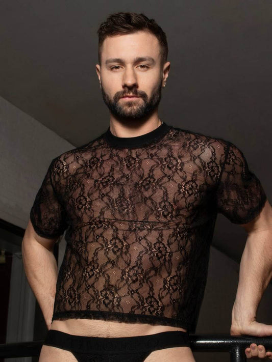 Man wearing a sheer black lace top against a dark background