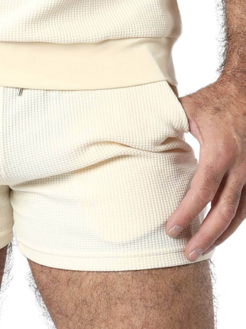 Close-up of a person wearing beige shorts and a matching top against a white background