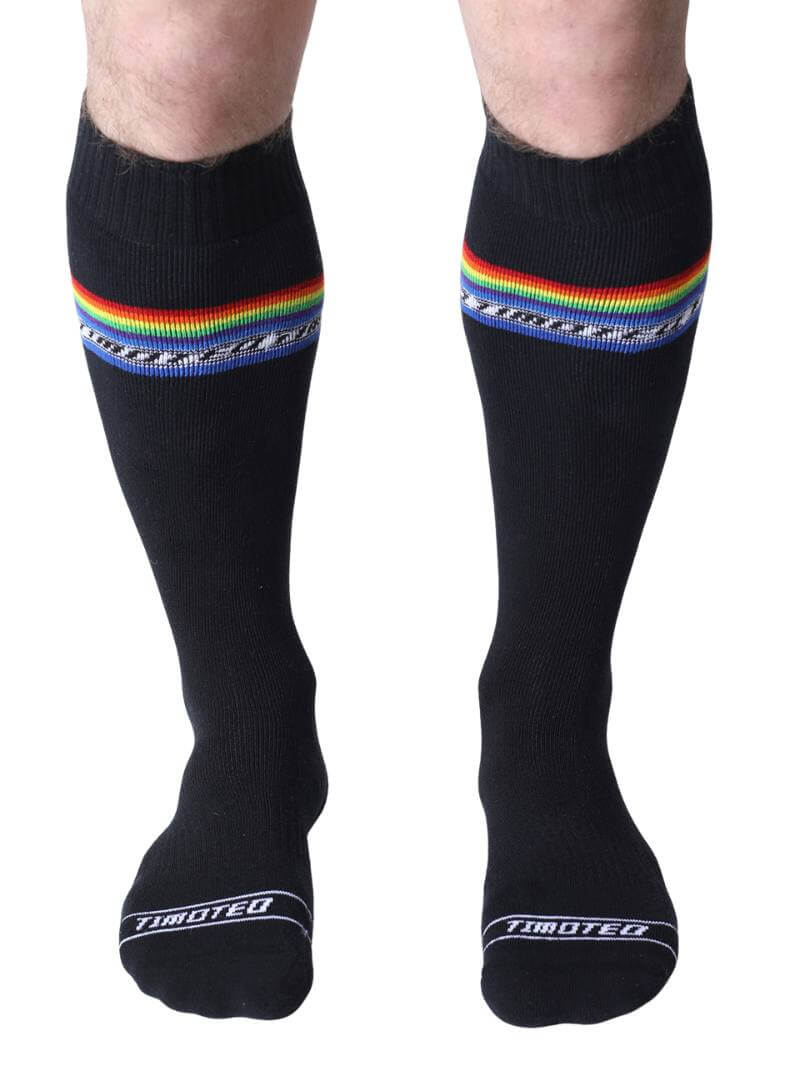 Black socks with rainbow stripes worn by a person on a white background