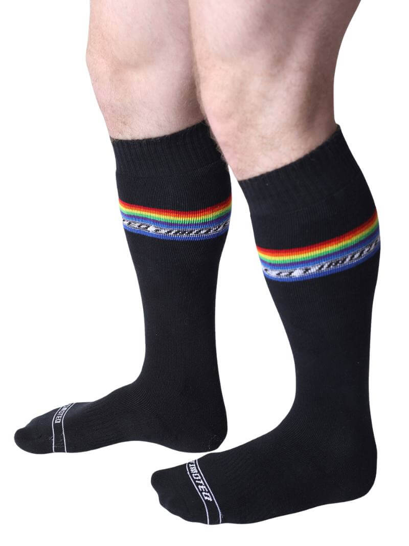Black socks with rainbow stripes worn by a person on a white background