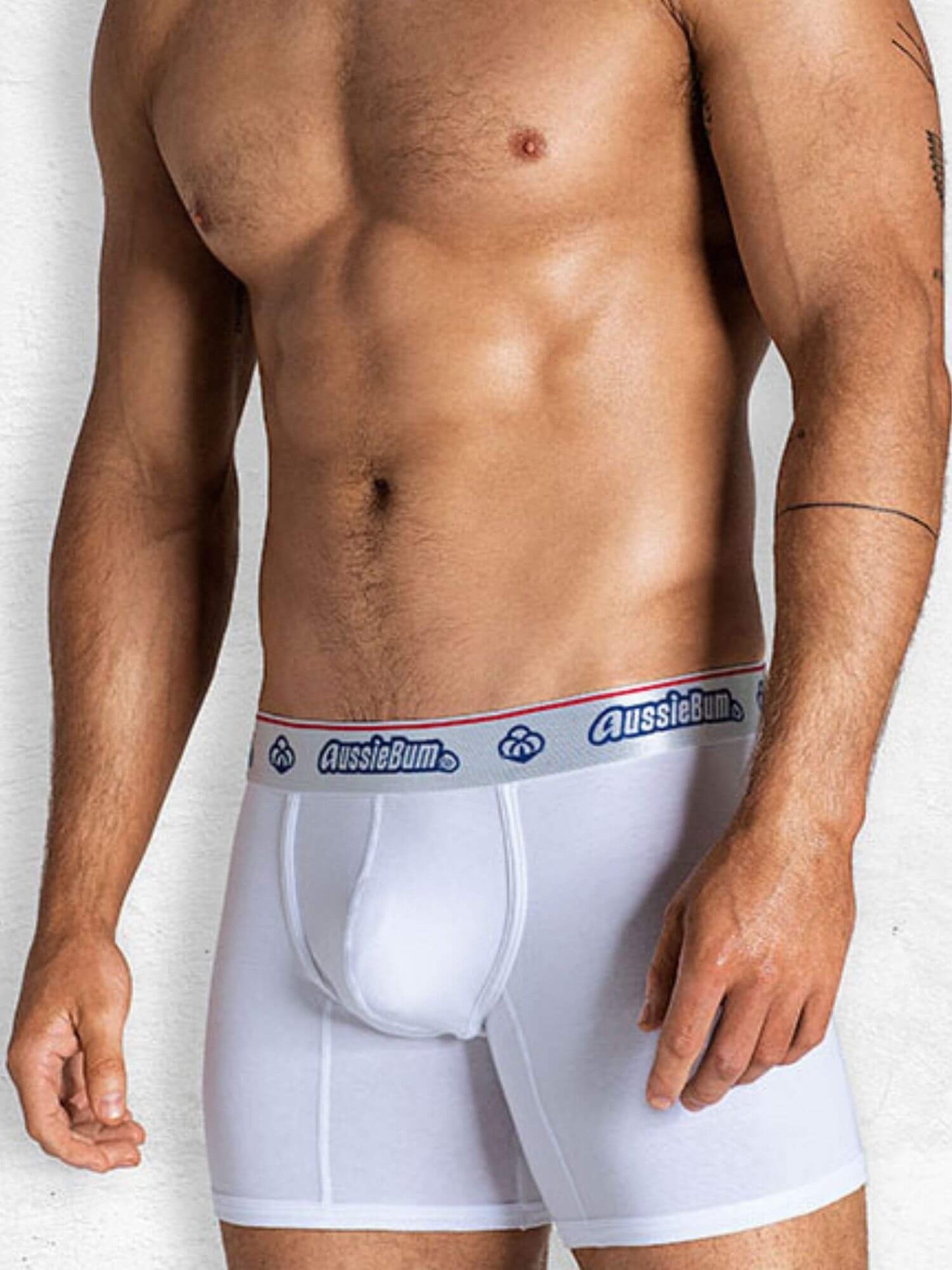 Man wearing white boxer briefs with a visible brand logo on a plain background