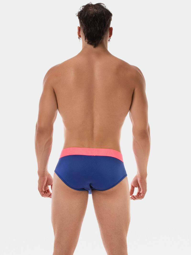 Man wearing blue swim briefs with pink waistband on a white background