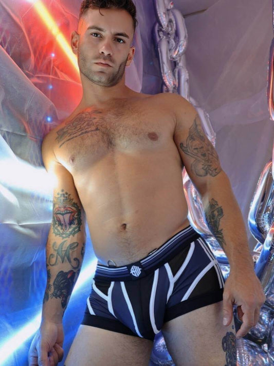 Man wearing black and white boxer briefs with a colorful, abstract background
