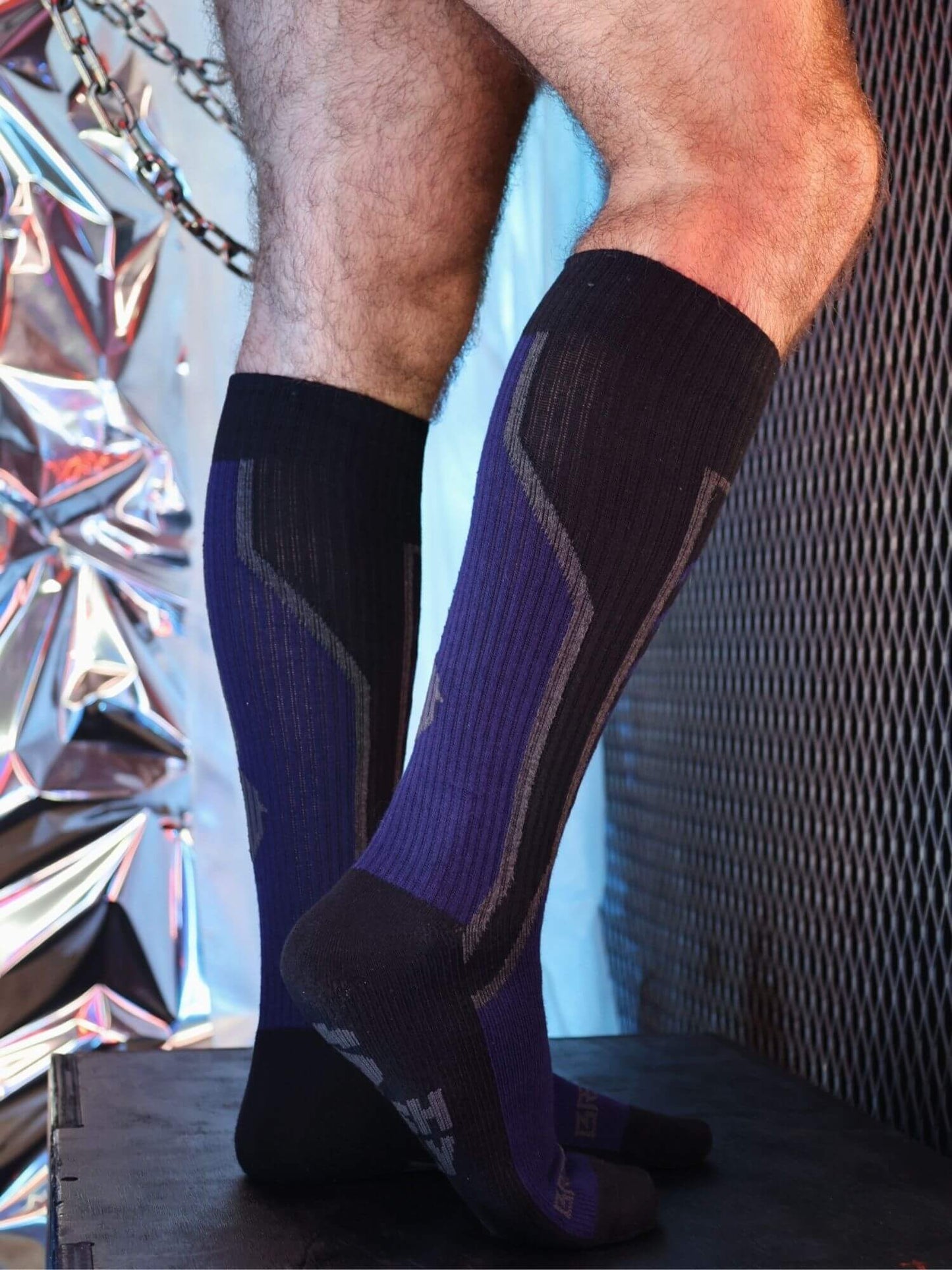 Person wearing black and navy socks with a reflective background