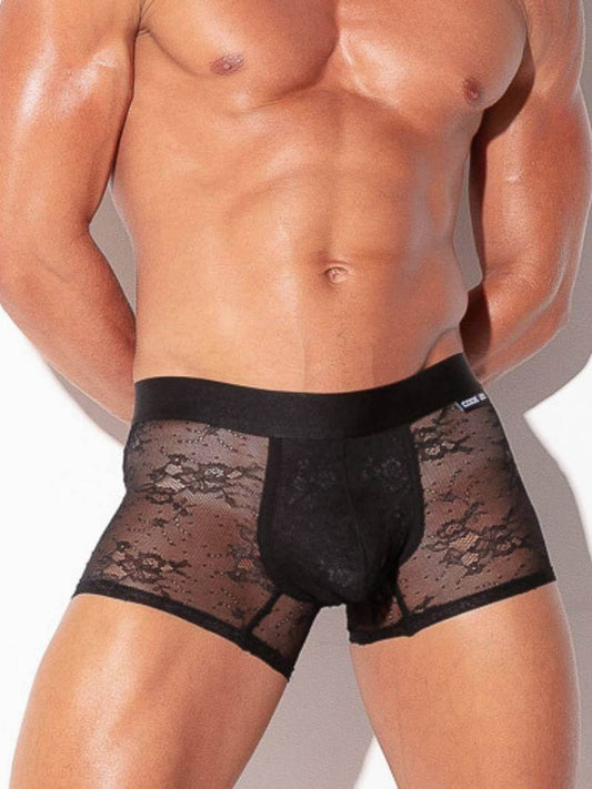 Black lace underwear worn by a muscular man on a plain background