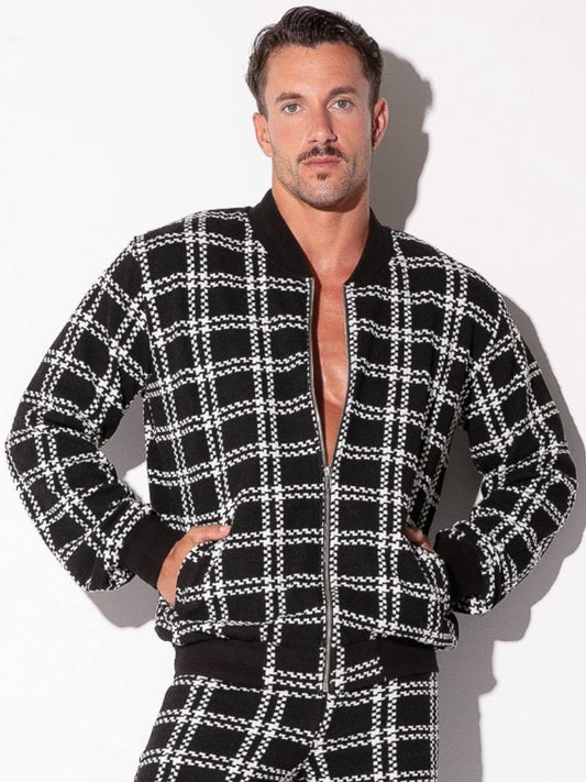 Man wearing a black and white checkered jacket with a plain background