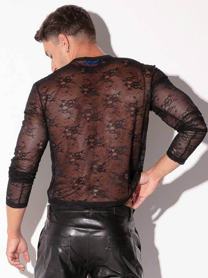 Person wearing a sheer black lace top and leather pants against a white background