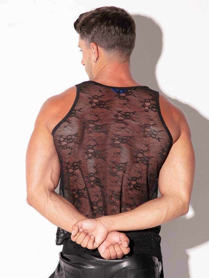 Man wearing a sheer black lace tank top against a white background