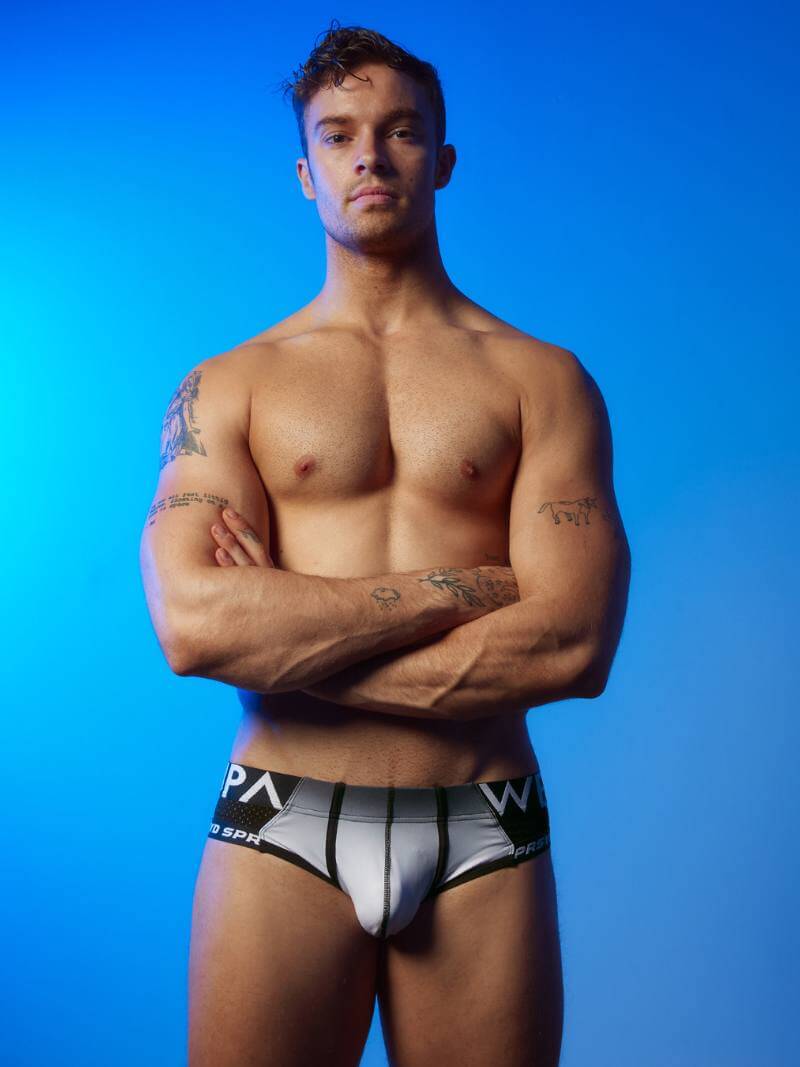 Man wearing black underwear with visible brand logos against a blue background