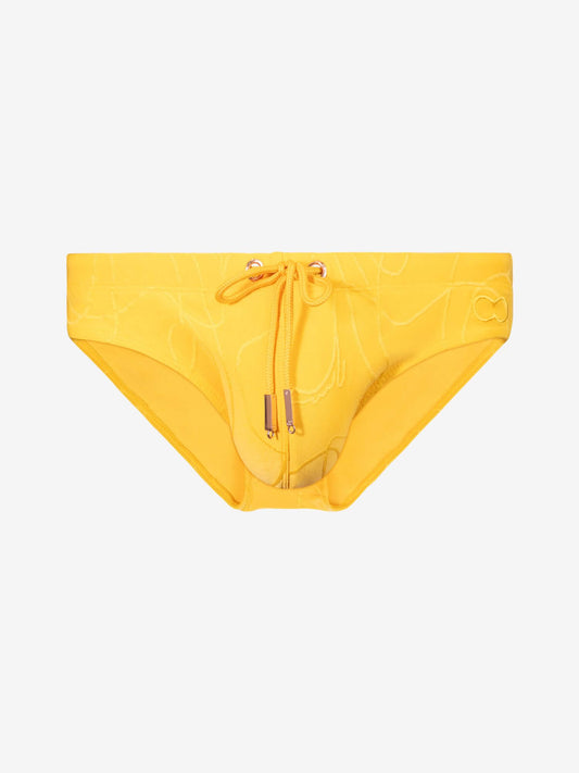 A pair of bright yellow bikini bottoms featuring a subtle tonal abstract pattern, a front drawstring tie, and a small gold-tone  detail at the center front, displayed against a solid light gray background.