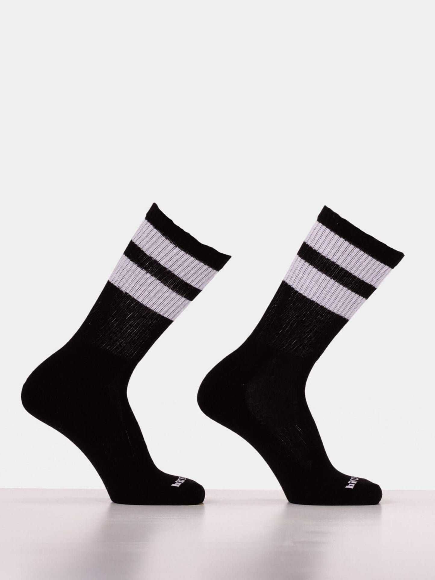 A pair of black crew socks with two white horizontal stripes near the cuff, displayed on invisible forms against a light gray background.