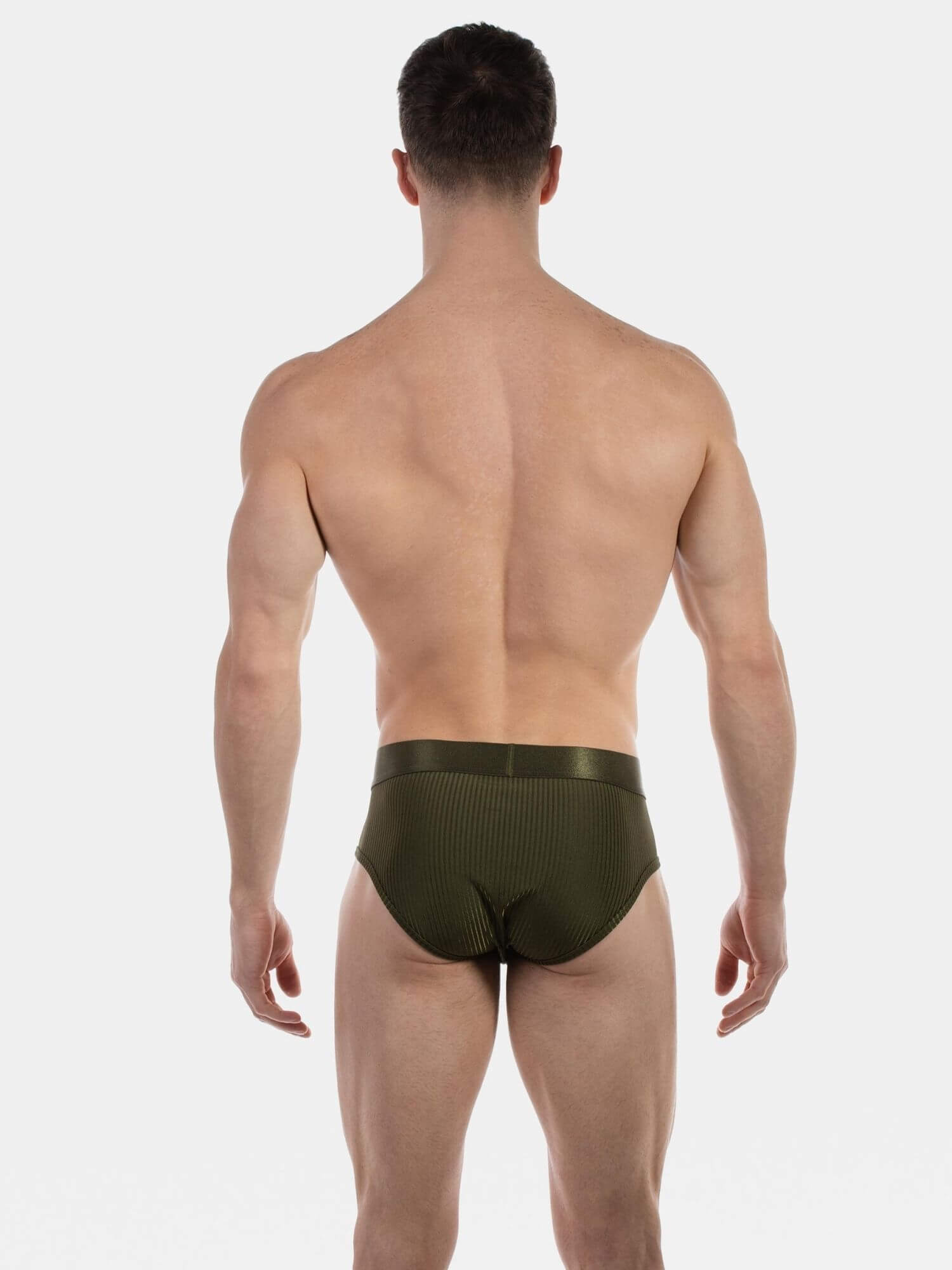 Rear view of a man wearing olive green ribbed briefs against a light gray studio background.