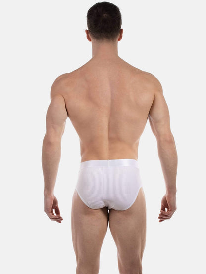 A man viewed from the back wearing white ribbed briefs against a light gray studio background.
