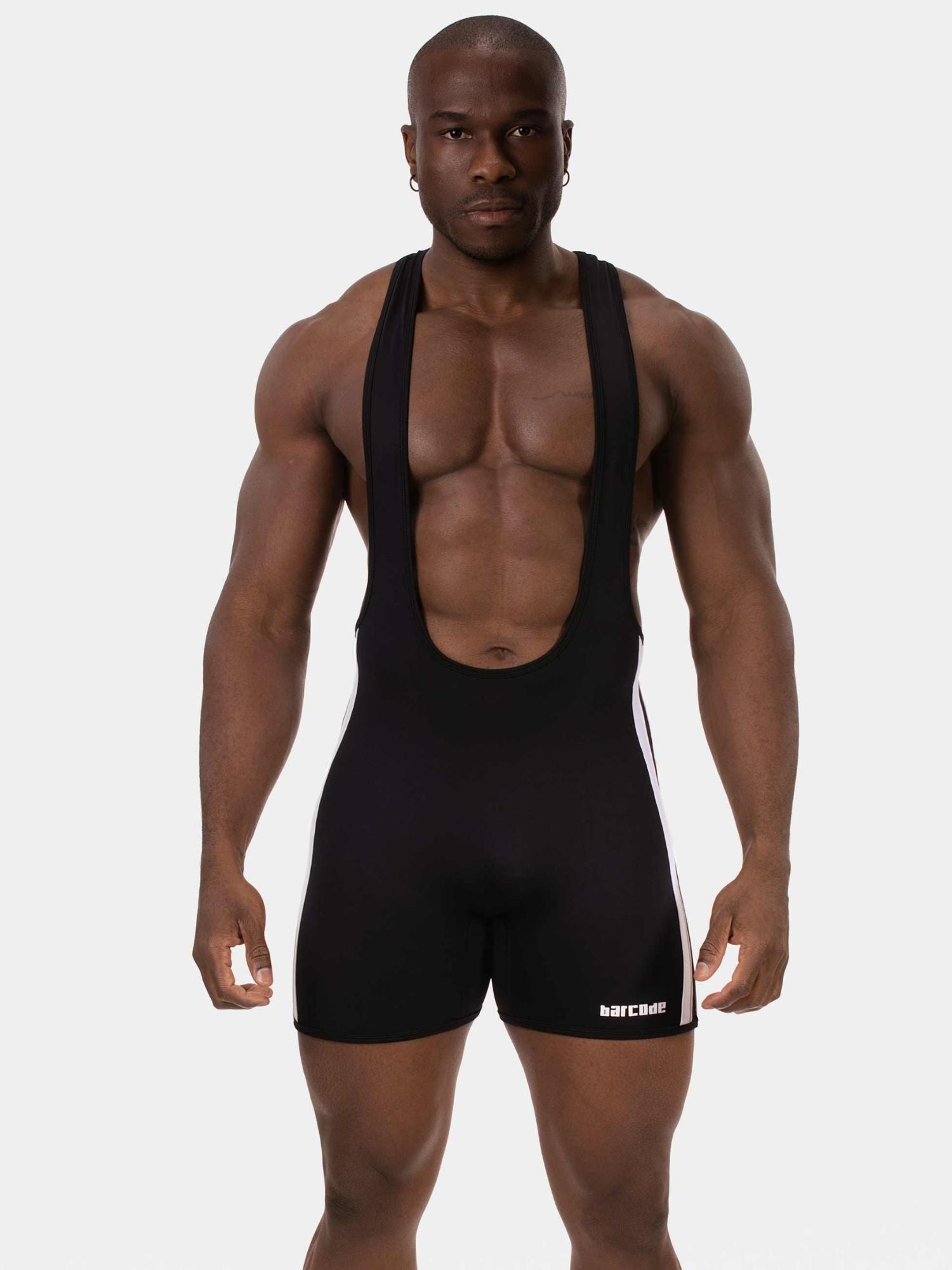 A muscular man modeling a black athletic singlet with wide shoulder straps and a white side stripe, standing against a light gray studio background. The brand name is visible in white on the lower right leg of the singlet.
