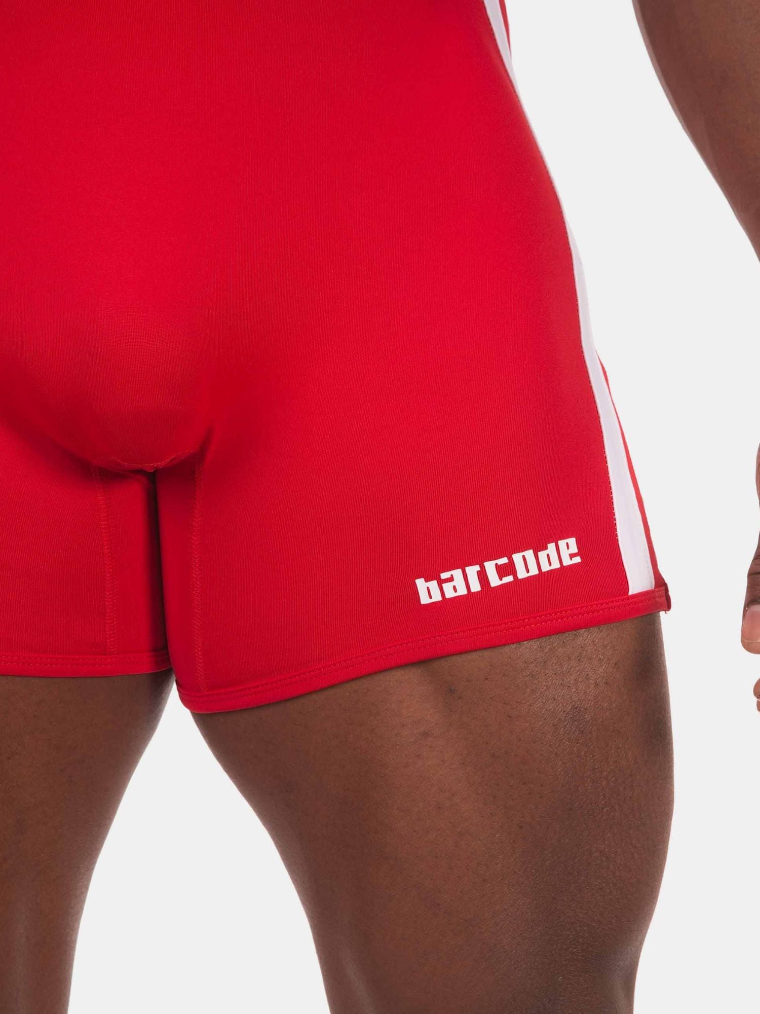 Close-up of a person wearing bright red athletic shorts with a white side stripe and the word 'barCode' printed in white near the hem, against a light gray background.